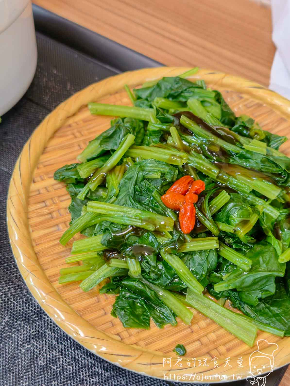 竹編盤上一份燙地瓜葉淋上店家自製醬汁與少許辣椒