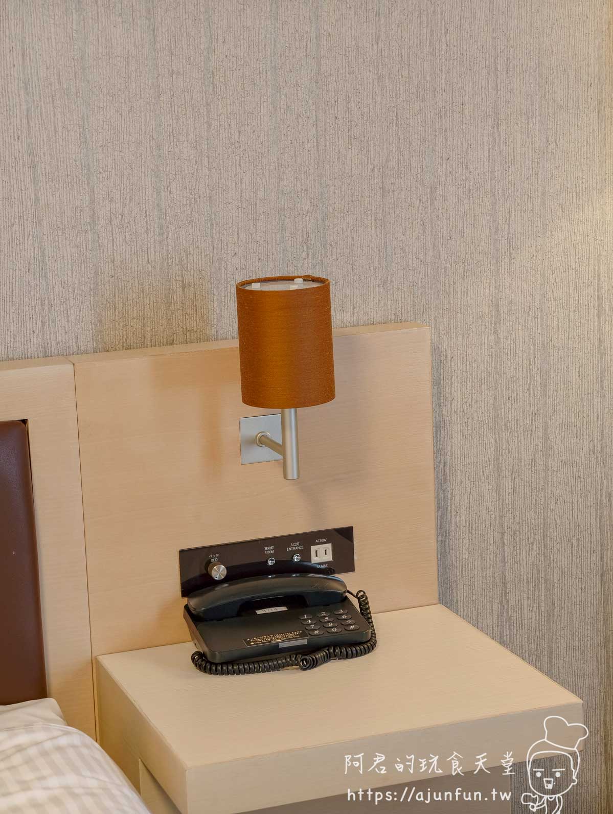 成田 Richmond Hotel 客房床頭夜燈與電話機，橘色燈罩搭配木質床頭板