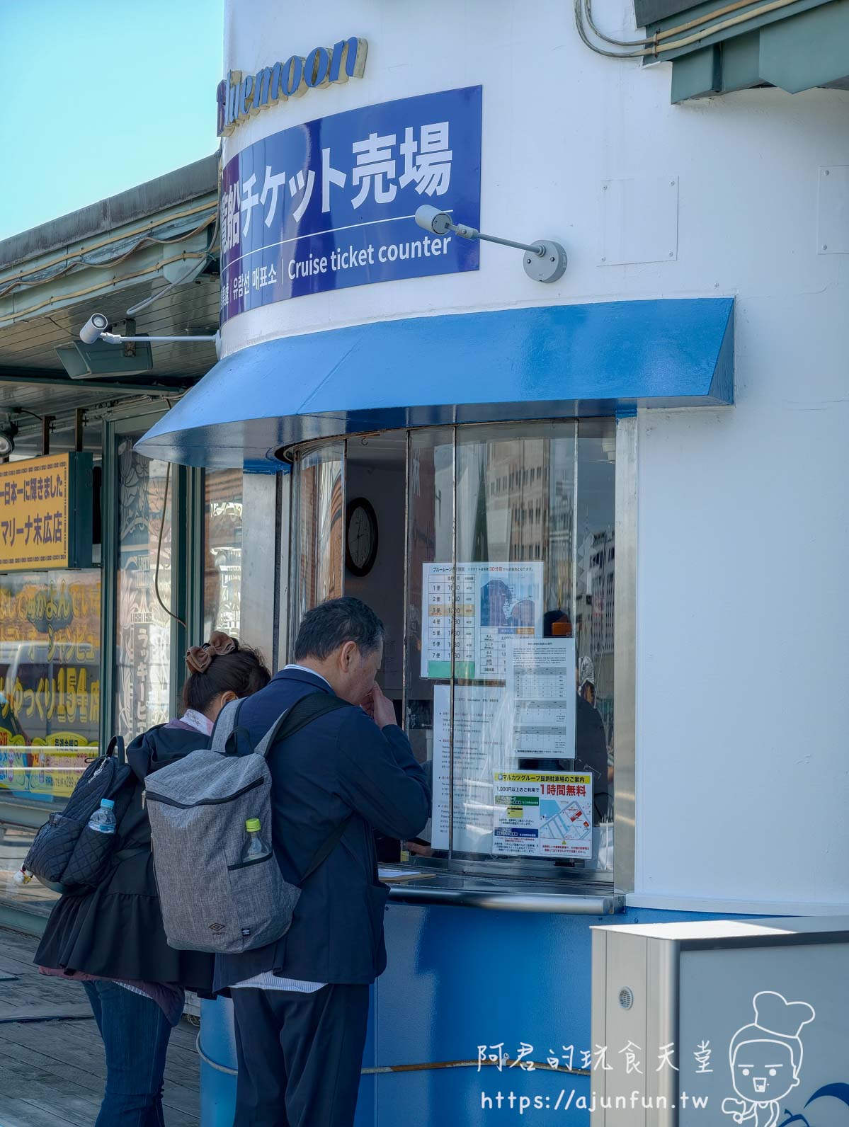 【函館景點】 Bluemoon 港內遊覽船攻略 2026|怎麼搭、票價多少、坐哪個位子才划算 - 第4張圖 Bluemoon 售票窗口實景 旅客對窗購票 日文告示海報 函館港碼頭 - 阿君的玩食天堂