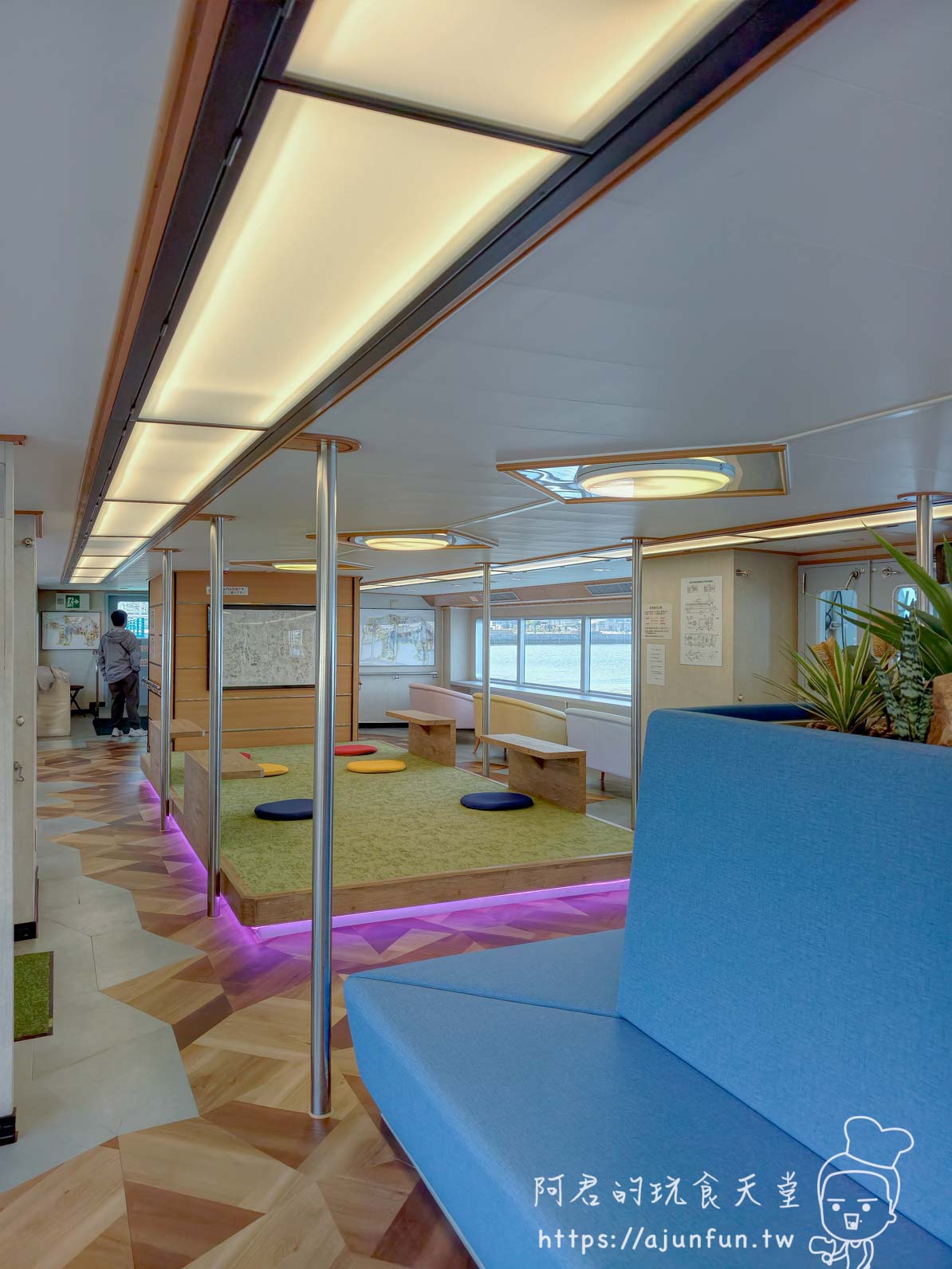 【函館景點】 Bluemoon 港內遊覽船攻略 2026|怎麼搭、票價多少、坐哪個位子才划算 - 第17張圖 Bluemoon 2F 上層艙全景 木質人字地板 藍色L型沙發 席地坐墊區 LED燈帶紫色間接光 - 阿君的玩食天堂