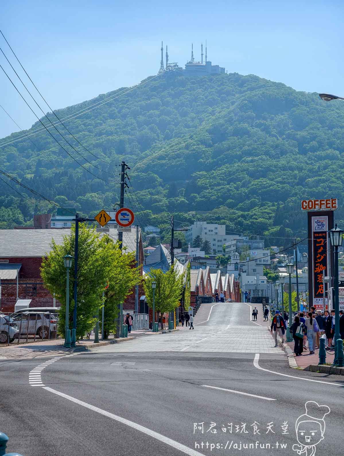 金森紅磚倉庫旁坡道仰望函館山頂天線晴天行道樹新綠