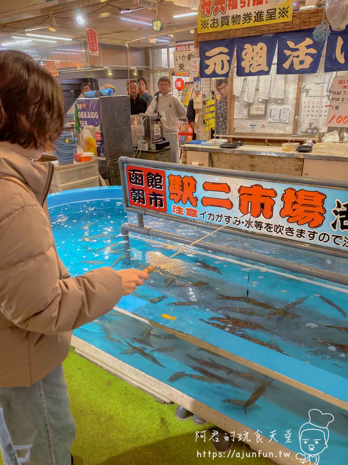 【函館朝市美食】元祖活烏賊釣堀|現釣現切刺身體驗(2026) - 第7張圖 元祖活烏賊釣堀 同行者持竹竿在藍色水槽邊垂釣烏賊 - 阿君的玩食天堂