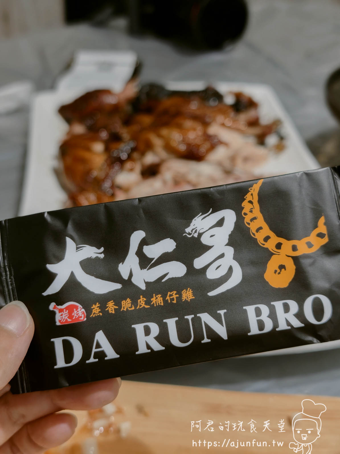 大仁哥蔗香脆皮桶仔雞 品牌黑色包裝袋與背景烤雞 - 阿君的玩食天堂